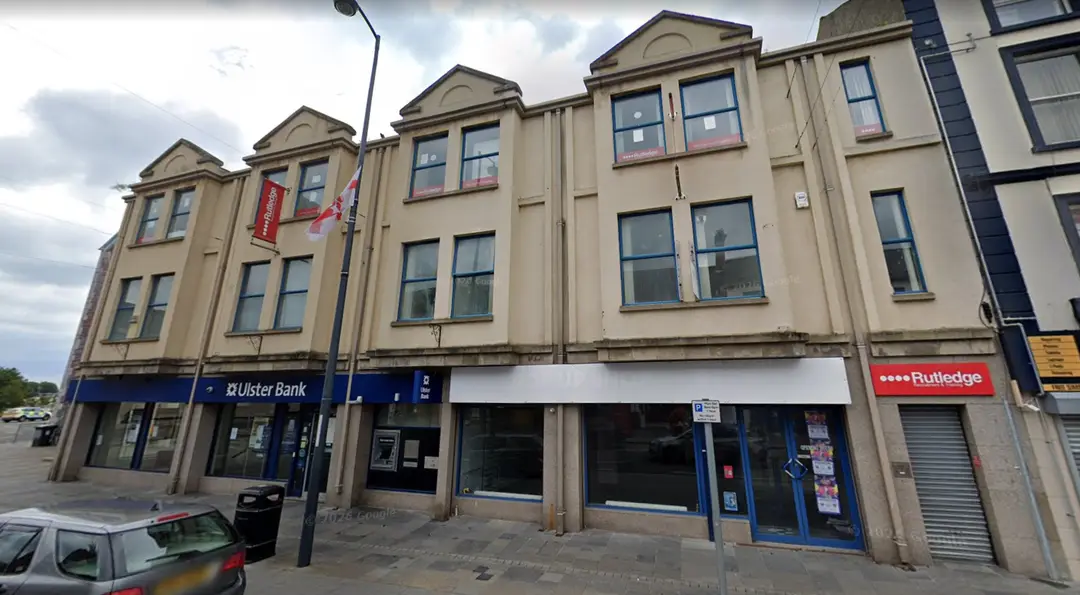 Rutledge Recruitment & Training Carrickfergus branch, red shopfront on the right of a cream three-storey terrace beside Ulster Bank on High Street.